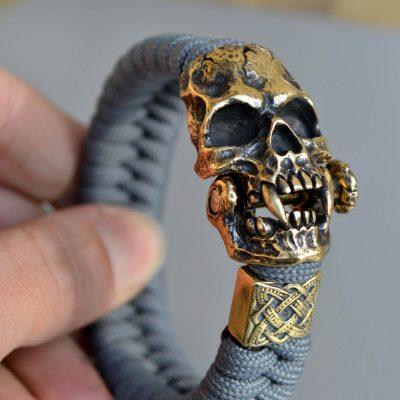 Фото плетеный серый браслет из паракорда с застежкой череп вампира и бусиной